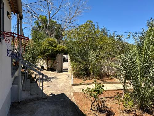 a walkway leading to a house with bushes and trees at Surfers' Cottage in Anavissos