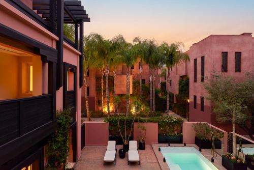 an apartment patio with a swimming pool and buildings at Hôtel & Ryads Barrière Le Naoura in Marrakech