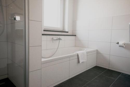 a white bathroom with a bath tub and a window at Ferienhaus am Mühlenweiher im Allgäu in Leutkirch im Allgäu