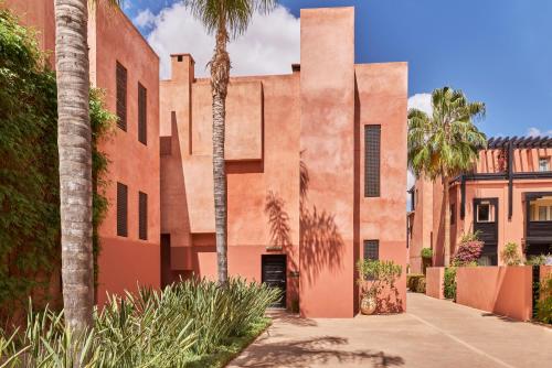an exterior view of a building with palm trees at Hôtel & Ryads Barrière Le Naoura in Marrakech