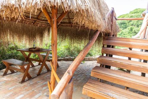 a bench and a table and a straw umbrella at East Africa Safaris in Chizavane