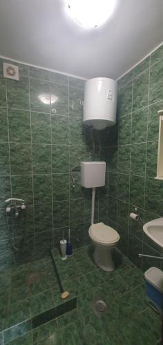a green tiled bathroom with a toilet and a sink at Aurora Spa in Kunje