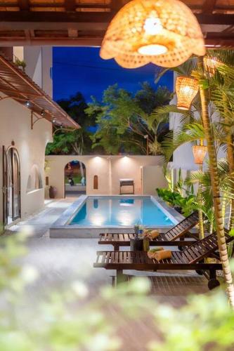 a swimming pool with lounge chairs next to a house at Coastal Village An Bàng Hội An in An Bang