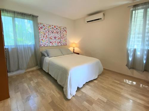 坎昆Habitación dentro de un departamento muy bien ubicado的一间卧室，有一张白色的床和一扇窗户