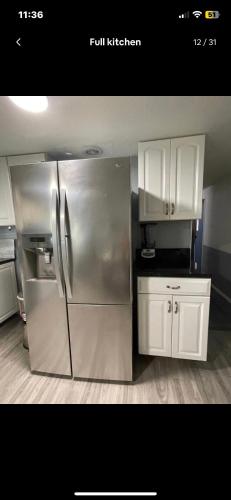 a kitchen with a stainless steel refrigerator and white cabinets at Tiny but cozy manufactured house in Tampa