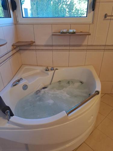 a jacuzzi tub in a bathroom with a window at Aurora Spa in Kunje