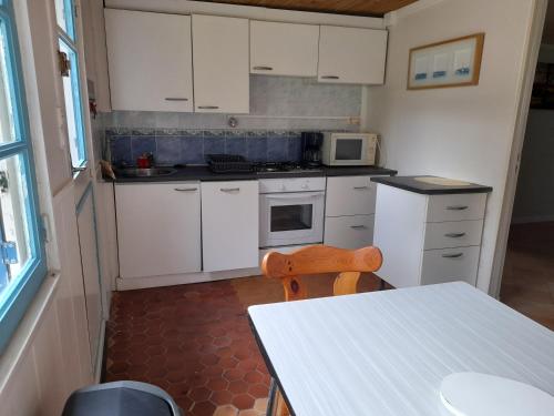 une cuisine avec des armoires blanches, une table et un micro-ondes dans l'établissement la nature, à Plouha