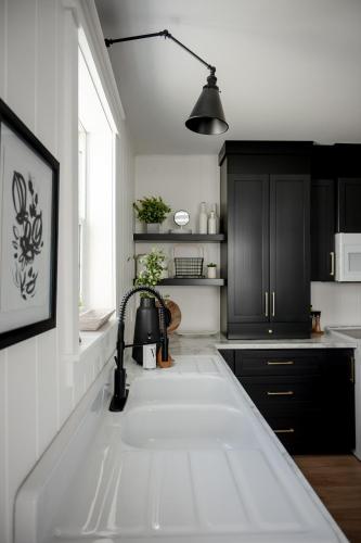 a kitchen with black cabinets and a white counter top at The cozy place in Campbellton