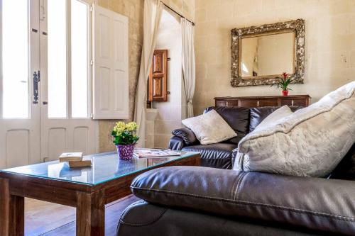 a living room with a leather couch and a table at Ta Karmnu in Għasri