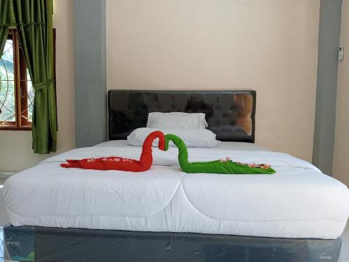 a bed with two red and green swans on it at Yusilver Guest House in Labuan Bajo
