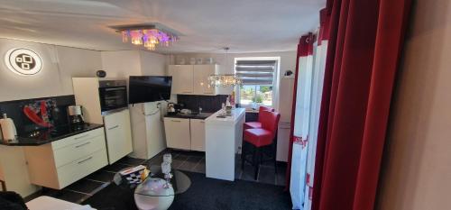 a kitchen with white cabinets and a red stool at Am alten Siel in Wilhelmshaven