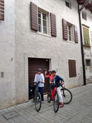 three people on bikes in front of a building at Affittacamere Casa Bliss in Venzone