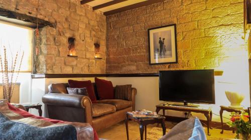 a living room with a couch and a television at Commerce Cottage Rooms in Ripley