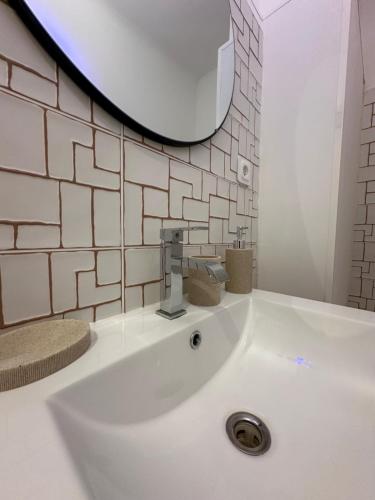 un lavabo blanc dans une salle de bain avec un miroir dans l'établissement La Rose des vents aux pieds des plages, à Palavas-les-Flots