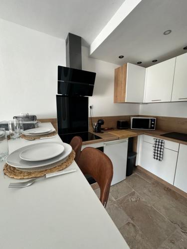 une cuisine avec une table avec des assiettes dessus dans l'établissement La Rose des vents aux pieds des plages, à Palavas-les-Flots