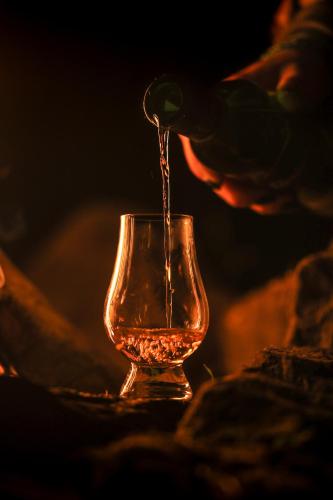 a person is pouring alcohol into a glass at SCHLOSS Roxburghe, part of Destination by Hyatt in Kelso