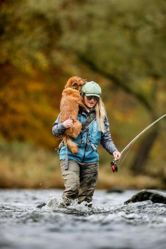 a woman holding a dog on her back while walking in a river at SCHLOSS Roxburghe, part of Destination by Hyatt in Kelso