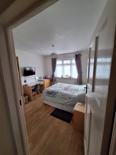 a bedroom with a bed and a desk and a window at Harrow B & B in Harrow Weald