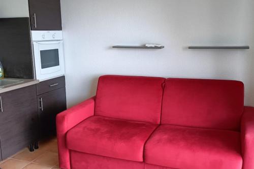 a red couch in a room with a kitchen at Studio près de la mer et marina in Gourbeyre