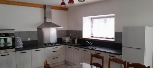 une cuisine avec des armoires blanches, un évier et une fenêtre dans l'établissement Gîte de la Grande Halle, à Servigny