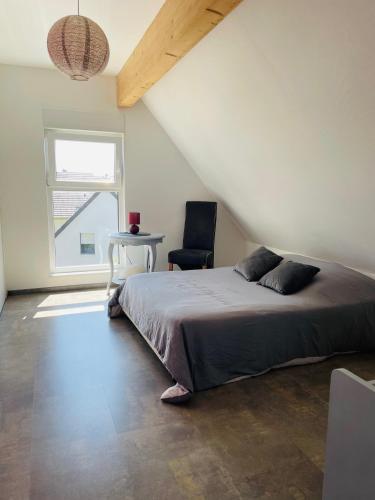 a bedroom with a bed and a chair and a window at Chez L en Alsace Maison indépendante 8 pers Jardin & Cour privative in Griesheim-près-Molsheim