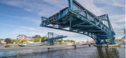 a blue bridge over the water with buildings in the background at Am alten Siel in Wilhelmshaven