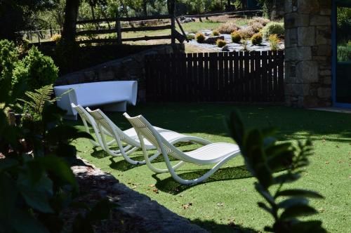 three white lawn chairs sitting in a yard at Pazo da Pena Manzaneda in Manzaneda