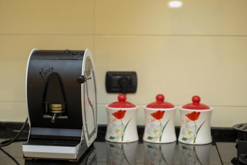 a coffee maker and three cups on a counter at Dapaj Luxury Residence in Vlorë