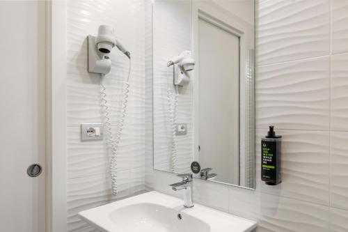 a white bathroom with a sink and a mirror at B&B Hotels Park Hotel Suisse Santa Margherita Ligure in Santa Margherita Ligure