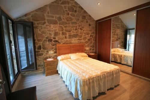 a bedroom with a bed and a stone wall at Casa en Fontecova in Cuntis