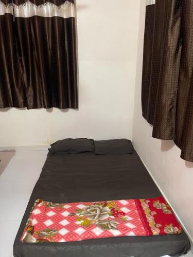 a small bed in a room with two windows at Humdum Holiday Homes 1 in Neral