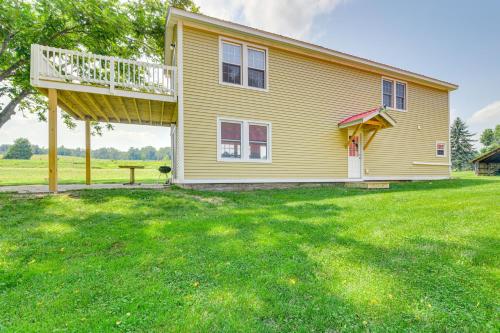 a yellow house with a deck on a yard at Adirondacks Cottage with Countryside Views! in Moriah