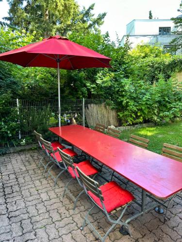 a red picnic table with chairs and an umbrella at Bijoux Wohnung auf dem Basler Hügel in Basel