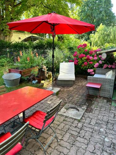a red table and chairs under a red umbrella at Bijoux Wohnung auf dem Basler Hügel in Basel