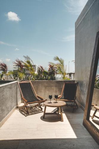 a patio with two chairs and a table on a balcony at Urbano by Sundara in Tulum
