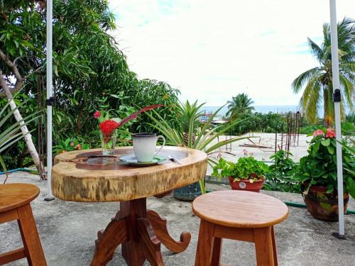 a wooden table with two stools and a table with a cup on it at ESPERANZA Casa de Huéspedes in Puerto Escondido
