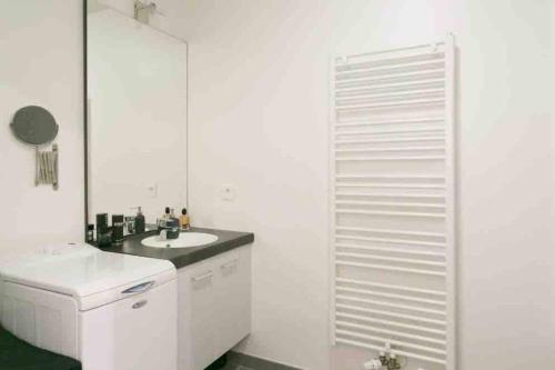a white bathroom with a sink and a mirror at Cozy & Quiet Getaway Just 300m from Paris with Free Private Parking in Gentilly