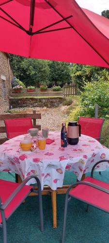 una mesa con una sombrilla roja sobre una mesa con sillas en LES RÊVES BLEUS, en Saint-Congard