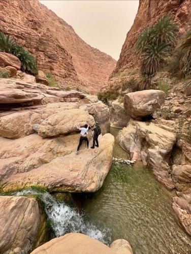 two people standing on some rocks in a river at Wild Dana Eco Lodge- Hotel-Eco-Camp in Dana