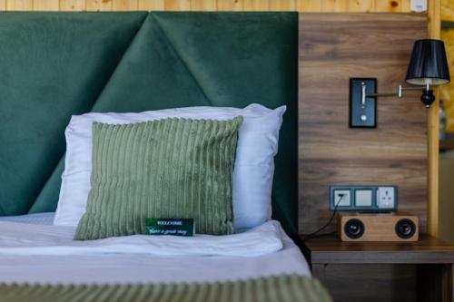 a bed with a green headboard with a pillow and an alarm clock at Glamping Martini Kvariati with pool in Batumi