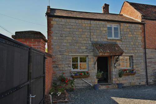 an old brick house with flowers in the window at The Cider House at Stathe Farm in Burrowbridge