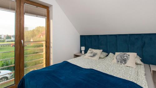 a bedroom with a bed with a blue headboard and a window at Dom Gościnny 2 Ogrodowa in Wiślinka