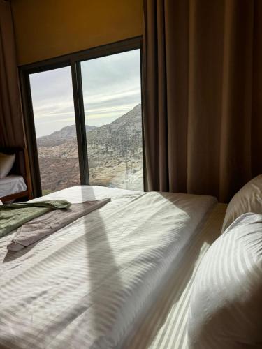 a bed in front of a window with a view at Wild Dana Eco Lodge- Hotel-Eco-Camp in Dana