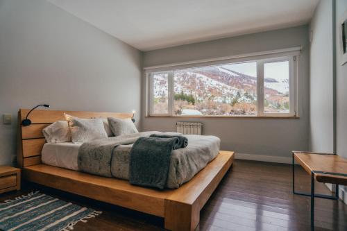 a bedroom with a bed and a large window at Ski Sur Apartments in San Carlos de Bariloche