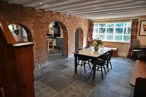 a dining room with a table and a brick wall at The Cider House at Stathe Farm in Burrowbridge