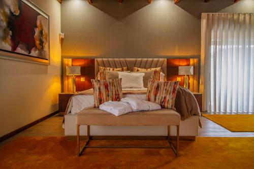 a bedroom with a bed and a bench with pillows at Casas das Pedrinhas by Paisagens Inéditas in Travanca