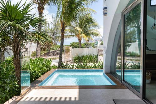 a swimming pool in the backyard of a house with palm trees at Villas Amanecer by Andiani Travel in Isla Mujeres