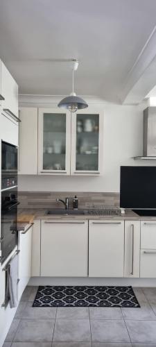 une cuisine avec des armoires blanches et un évier dans l'établissement SWEETY HOME - proche PARIS - Parking PRIVE, à Montreuil