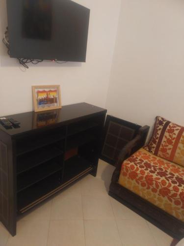een woonkamer met een bank en een tv aan de muur bij Mogador Authentique T6 in Essaouira