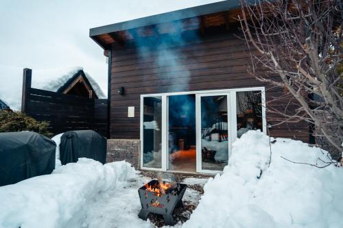 a fireplace in front of a house in the snow at Ski Sur Apartments in San Carlos de Bariloche